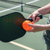 A person holding a pickleball and racket