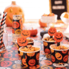 54 Halloween table cloth with close up of mini cups of nuts, paper straws, and other Halloween Party foods