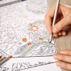 a person filling in a colouring book and using a green pencil