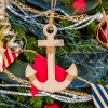 Nautical anchor gold Christmas decoration hanging on a coastal themed tree close up