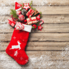 Red Christmas Stocking with White trim and white reindeer on it spilling out goodies on rustic wooden background
