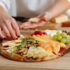 BLOG THUMBNAIL A person layering slices of cheese on a charcuterie board