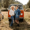 Lyndsay Lamb and Leslie Davis standing in field in front of vintage old red VW van
