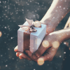 a person holding a gold gift box with gold ribbon tied on top