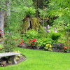 large backyard garden with flowers and a stone bench