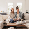 Leslie Lamb and Lyndsay Davis close up thumbnail sitting on couch smiling