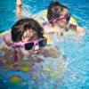 Two girls with brown hair and sunglasses swimming in pool with floaty ring. Square photo