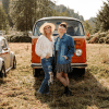 Leslie Davis and Lyndsay Lamb standing in front of vintage orange VW Bus in field.