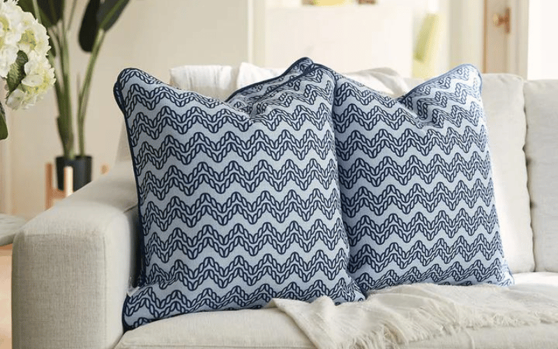 Two blue pillows placed on a white couch 