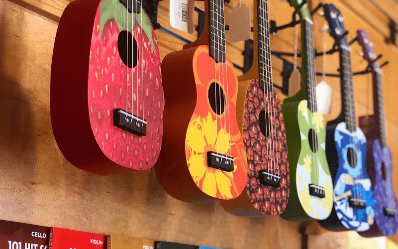 six brightly coloured guitars hung on a wall 