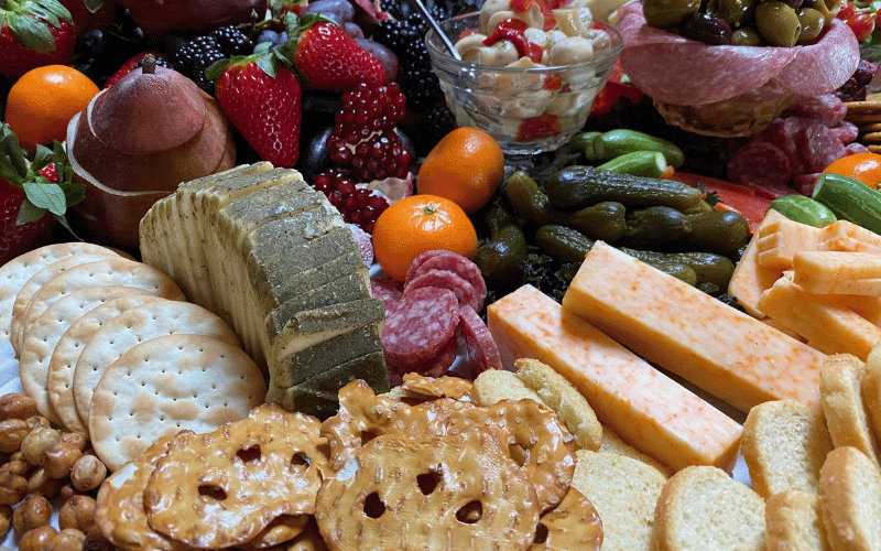A charcuterie board filled with pretzels, cheese, cured meats, and fruit