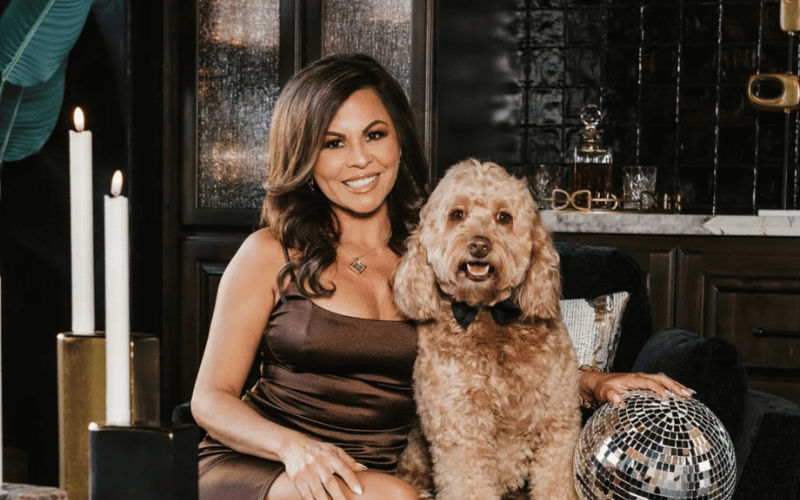 woman in a brown dress sitting on a coach with her dog with a candle in the background