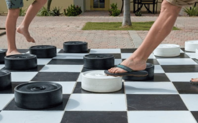 giant outdoor checkers board with people standing on the giant checker pieces 