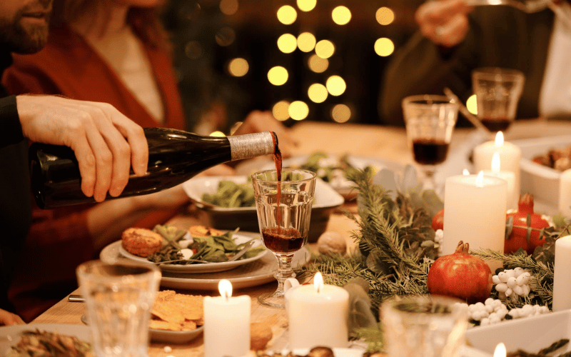 a Christmas dinner table with candles and wine glasses and wine bottles on top
