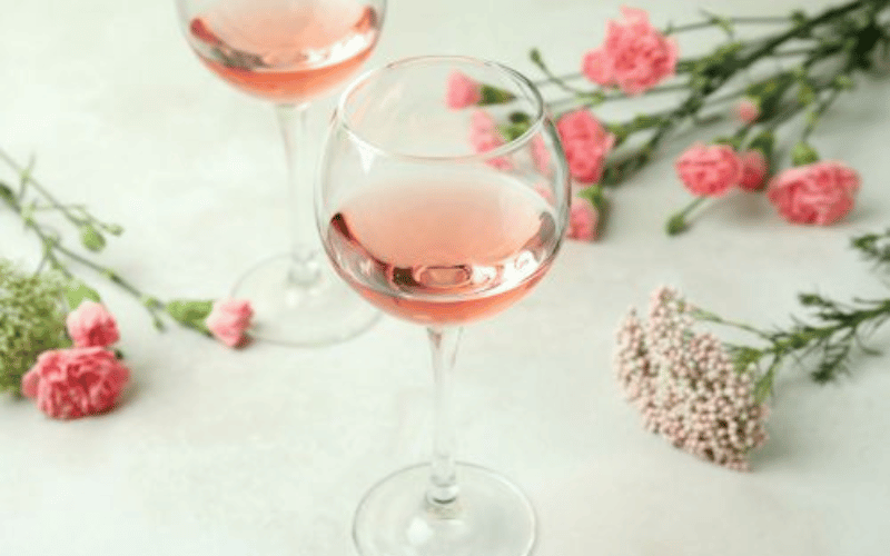 a glass of rosè with rose petals in the background