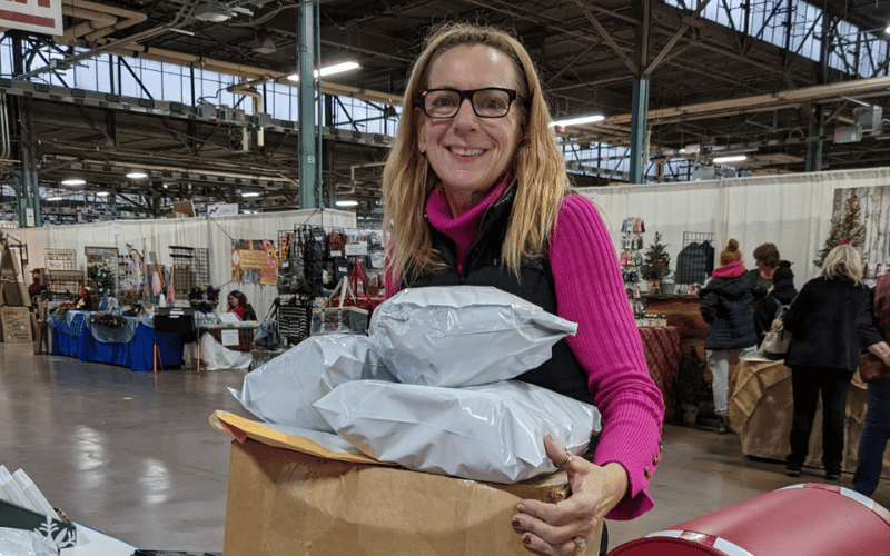 woman holding a cardboard box filled with postage packages inside