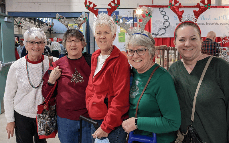 five elderly people wearing Christmas themed clothing