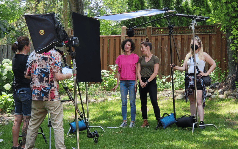 a film crew recording a video in a large backyard 
