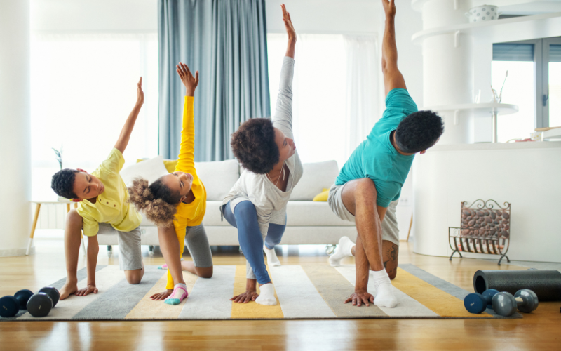 family of four in side lunch yoga pose with left arm reaching to the ceiling working out as a family