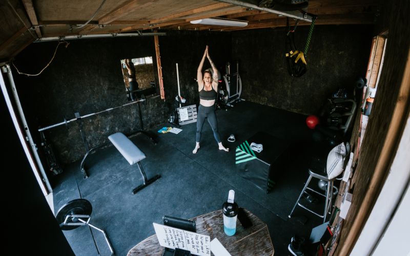 Woman working out wearing black in all black garage gym.