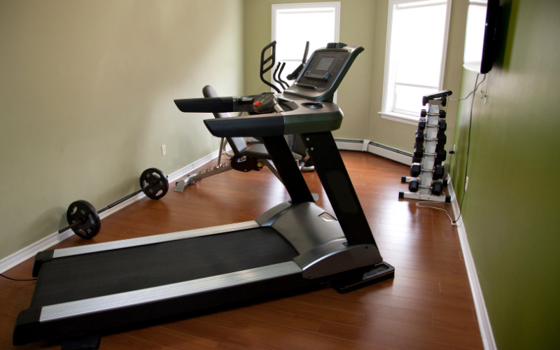 Black treadmill in narrow nook in green hallway