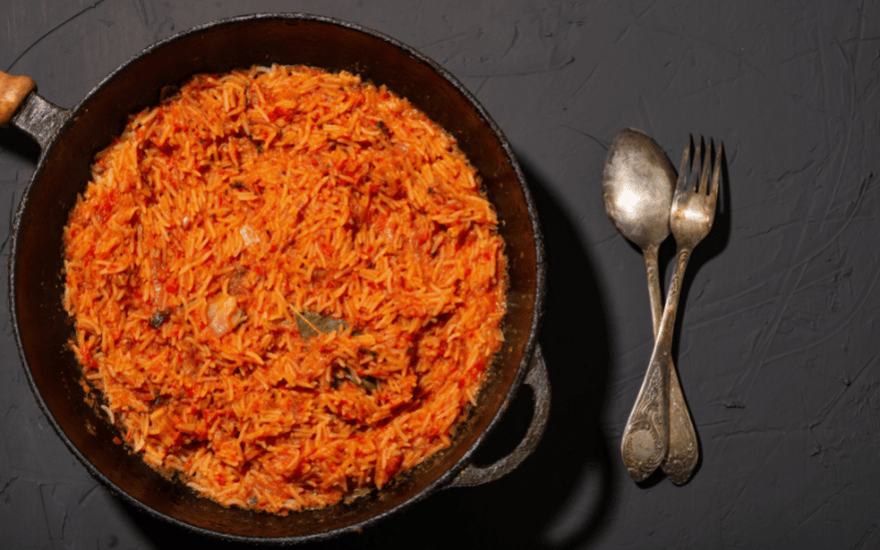 skillet full of cauliflower rice cooked in tomato sauce with vegetables and fresh herbs inside