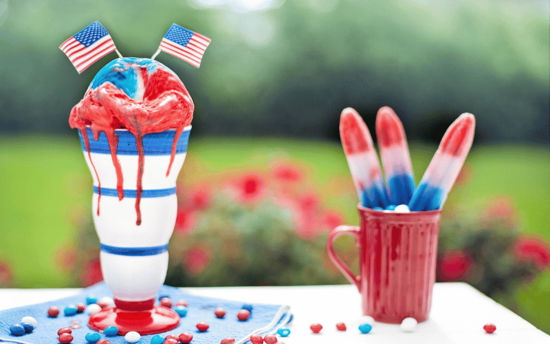 Red, white and blue custom slushies and popsicles on outdoor table for Independence Day