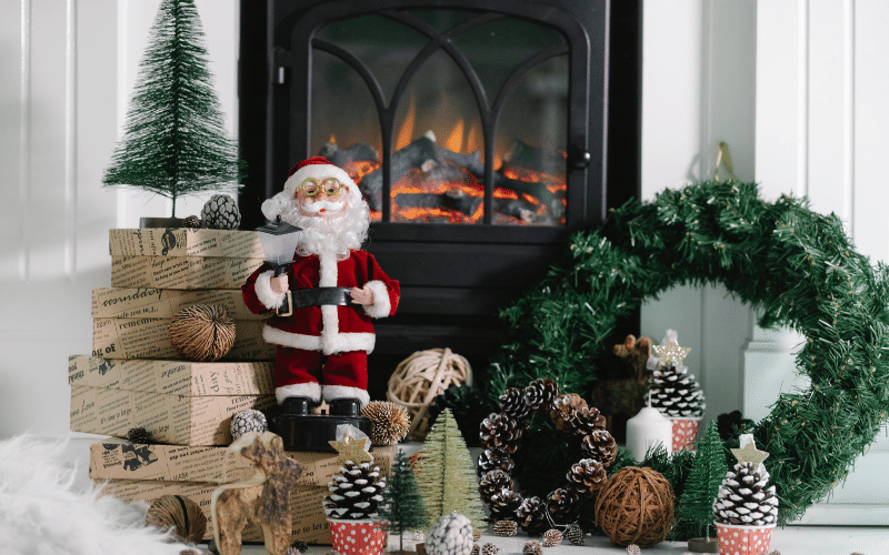 Christmas Decorations newspaper wrapped gift boxes, small Santa, pinecones in red disposable cups and wreath in front of fireplace