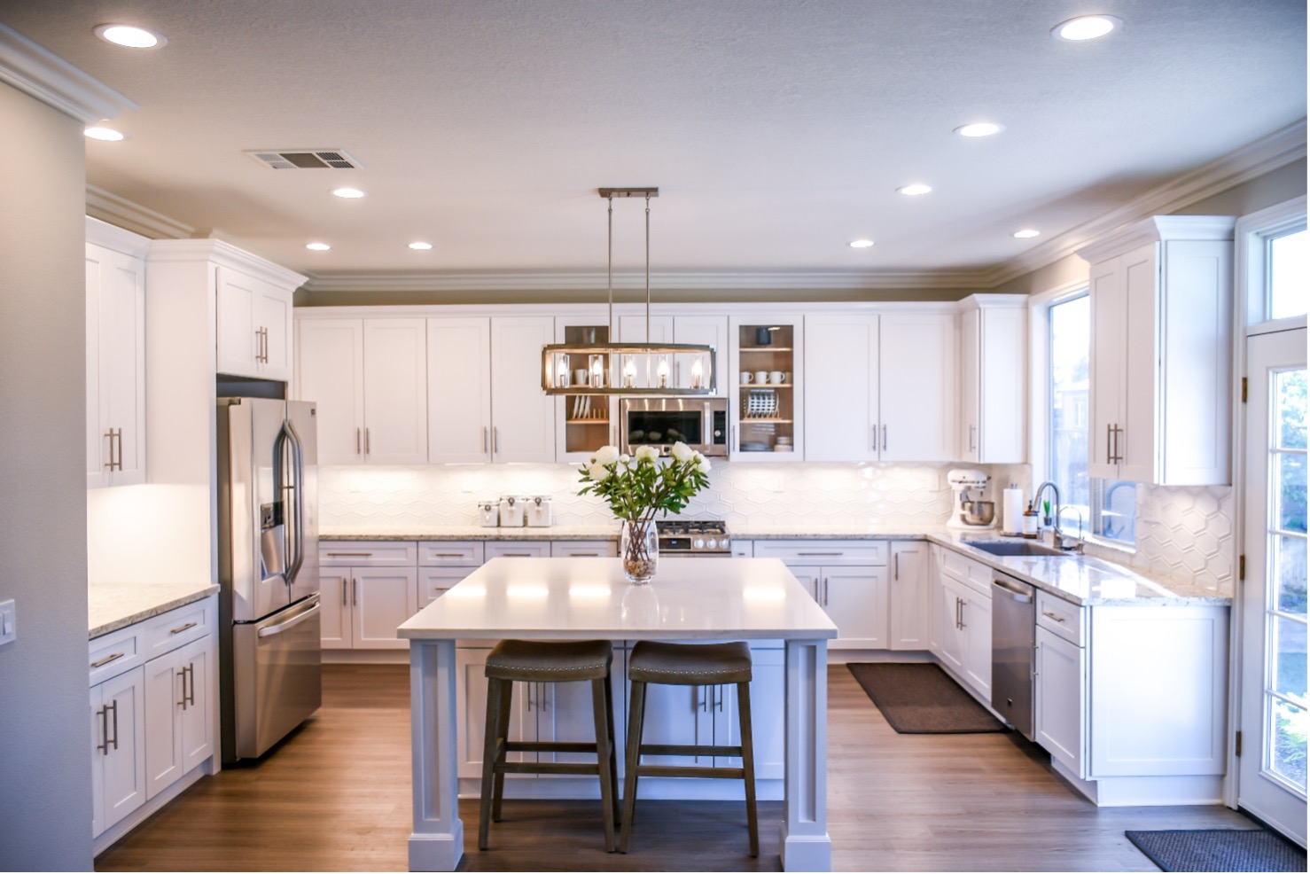 Nice white clean well lit kitchen with white roses on central island and stainless appliances