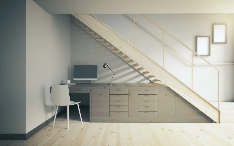 private desk, computer and white chair tucked away under stairs