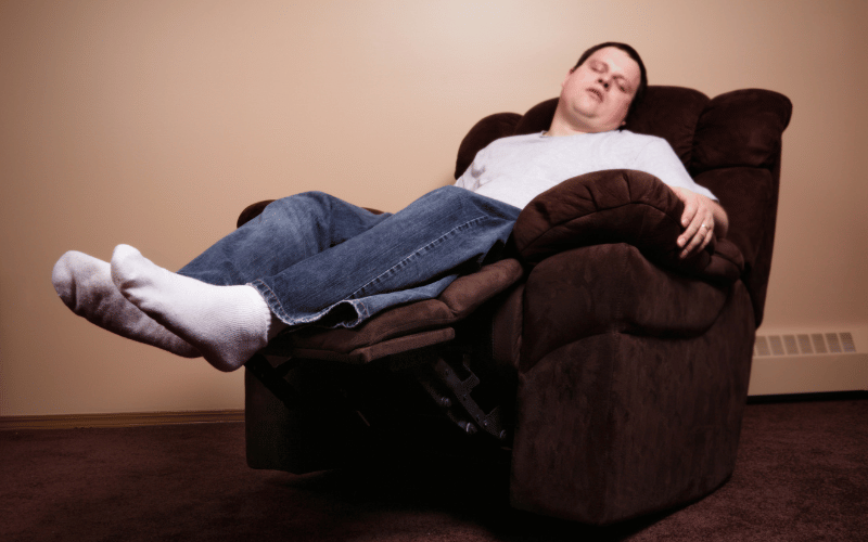 white middle aged man wearing white tshirt and jeans sleeping in brown recliner chair