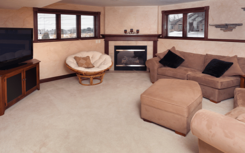 Large beige room with suede couches and chairs, a big screen TV and a fireplace