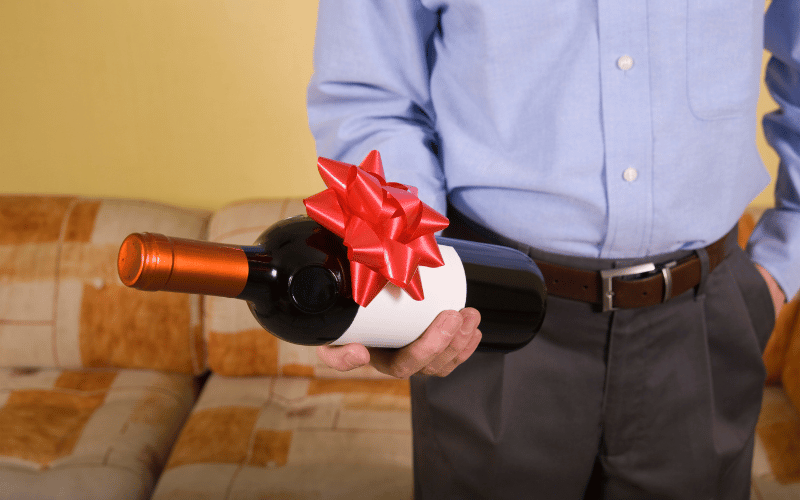 Man holding giftable bottle of red wine with a red bow